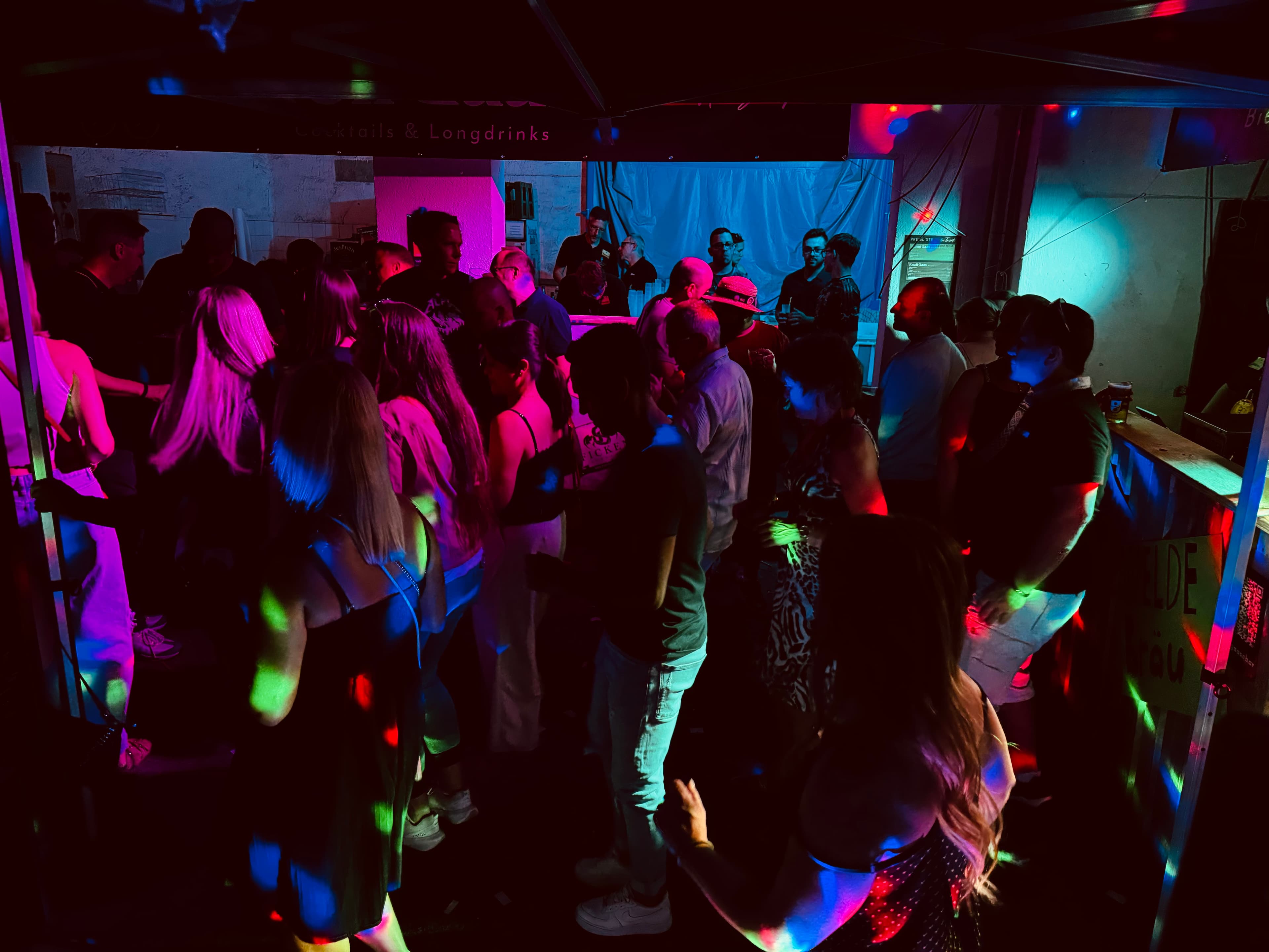 Volle Party-Bar mit tanzenden Gästen und farbigem Bühnenlicht
